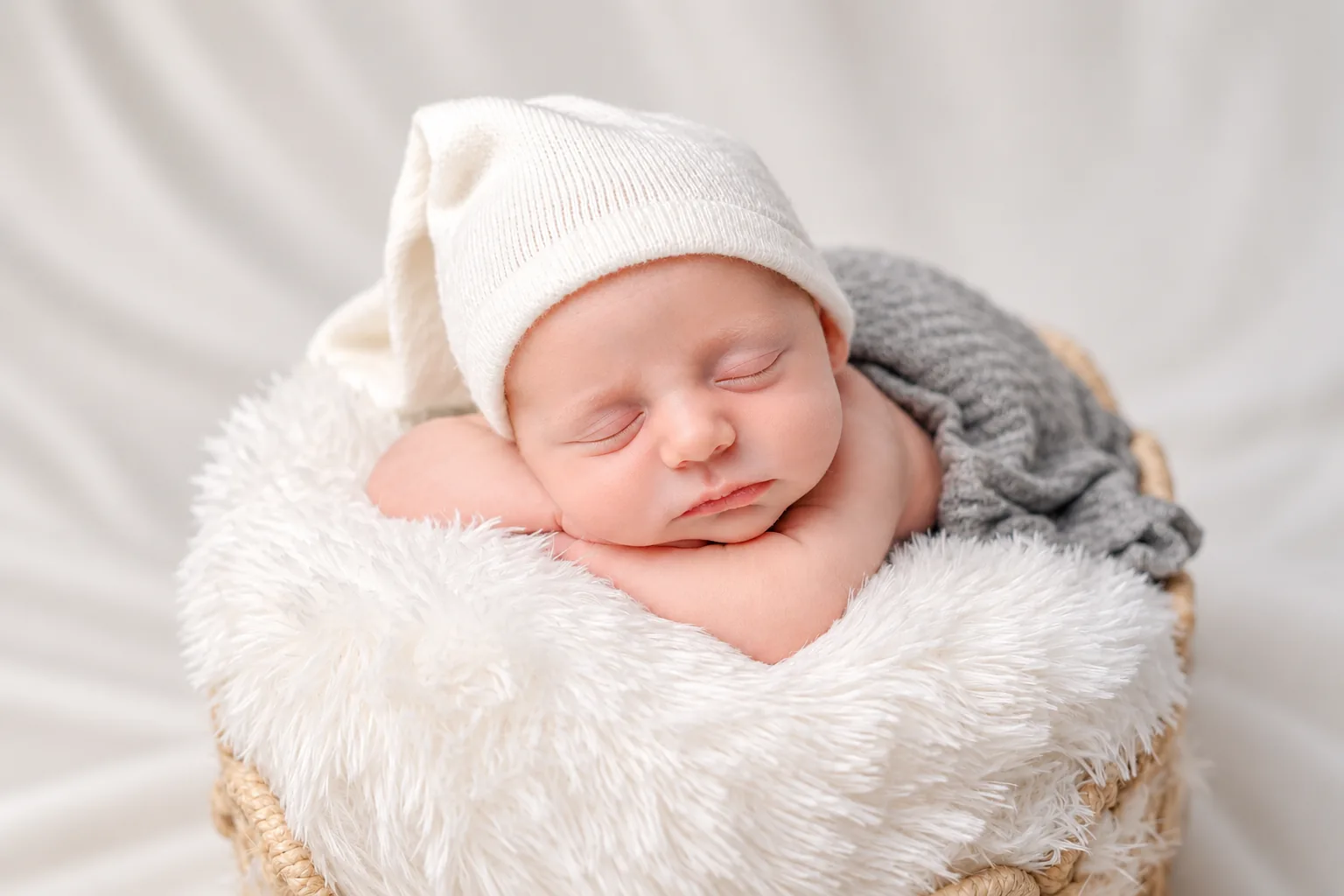 Sleeping newborn in a white hat in a cosy basket, photographed in Dubai