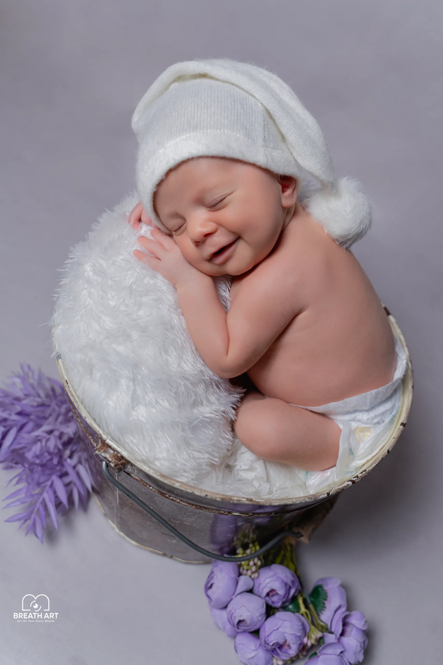 Smiling newborn curled on soft white fur