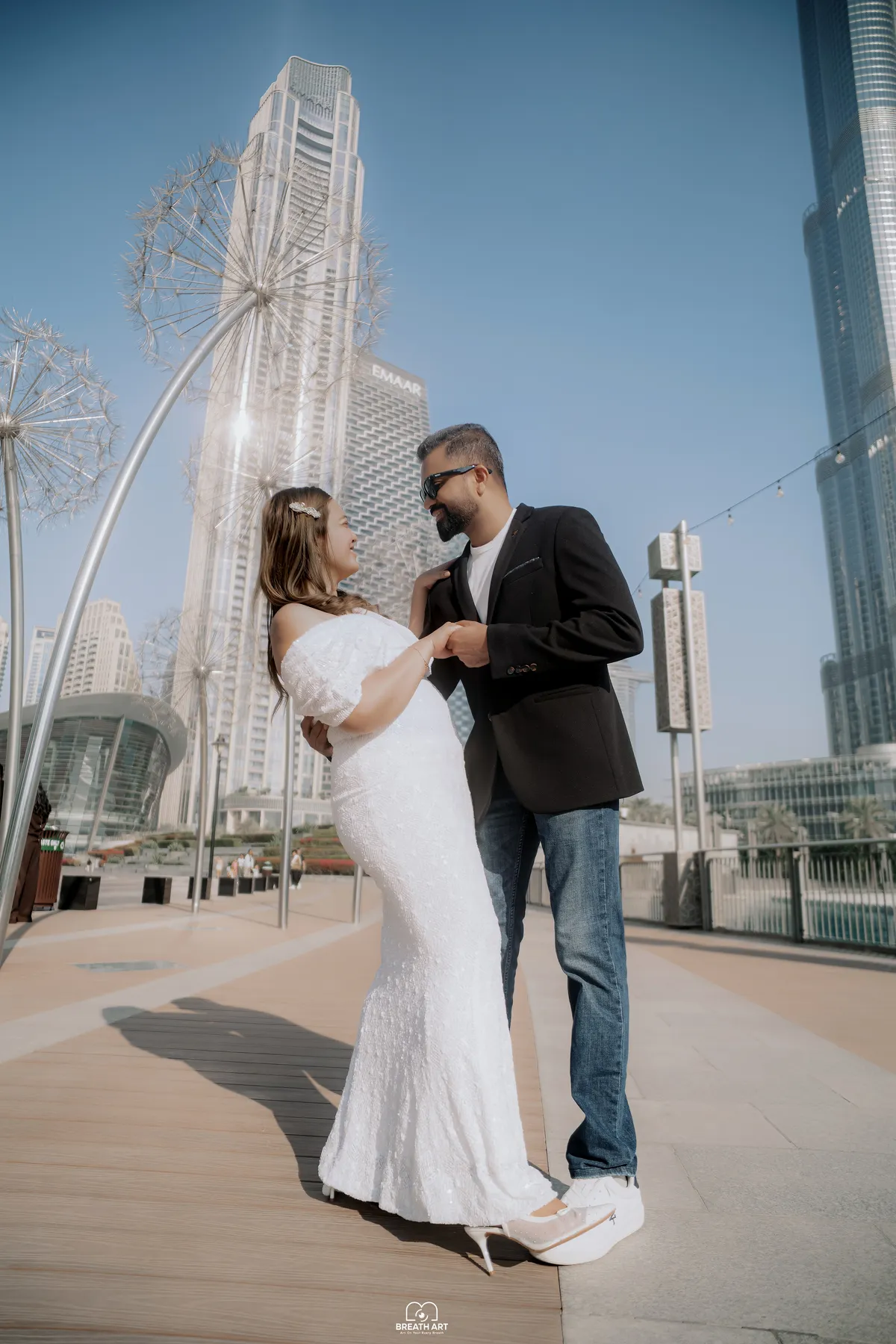 Couple holding hands under the dandelion sculptures near the Burj Khalifa, photographed by BreathART