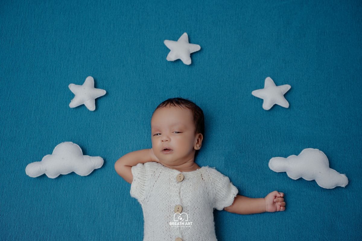 Clouds and sky newborn photoshoot theme on blue backdrop